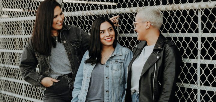 3 women standing beside gray metal fence